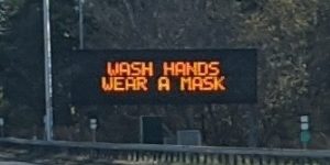 Digital sign by the highway: Wash hands, wear a mask.